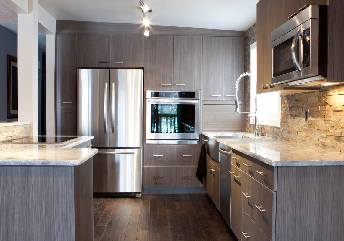 A modern kitchen with dark wood cabinets, stainless steel appliances, and a stone backsplash.